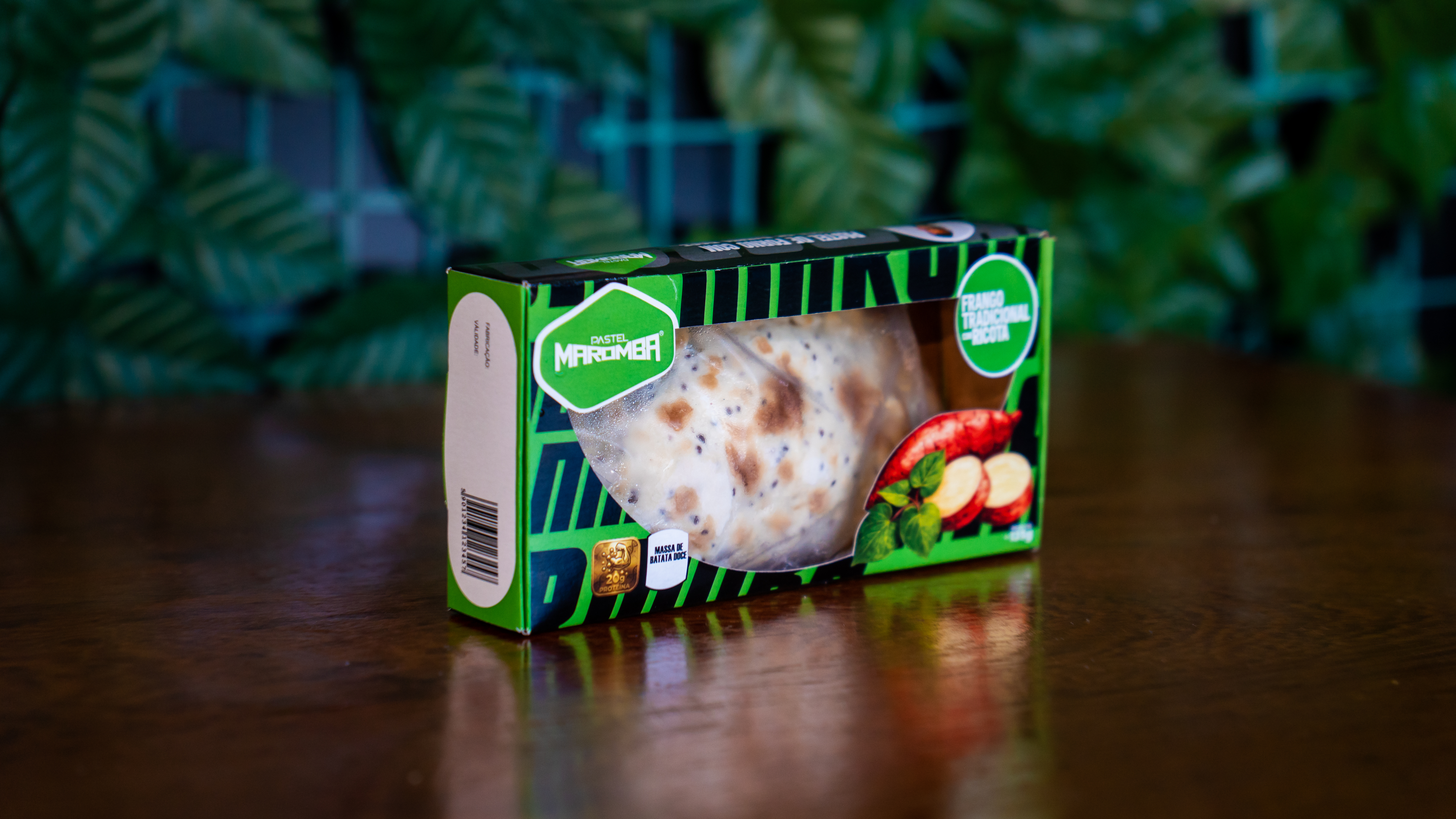 Caixa verde de Pastel Maromba com selo Frango Tradicional com Ricota sobre mesa de madeira